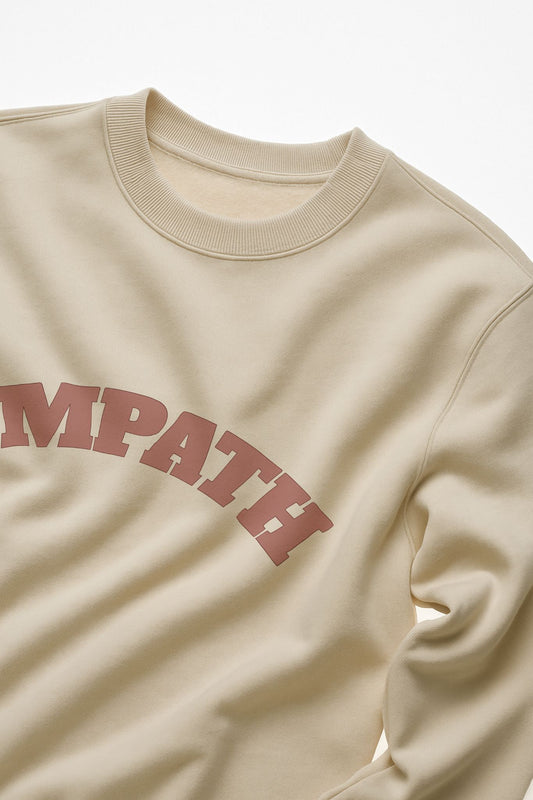Ivory FineAF crewneck sweatshirt showing “EMPATH” chest print close-up on fabric.