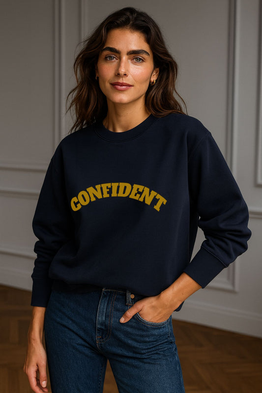 Model wearing FineAF CONFIDENT sweatshirt in navy — unisex organic cotton crewneck, minimalist design with gold arched lettering.