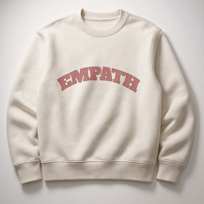 Ivory EMPATH Sweatshirt in organic cotton fleece with muted pink arched text, photographed flat against soft neutral background.