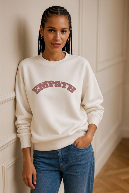 Model wearing FineAF Ivory EMPATH Sweatshirt made from organic cotton fleece, styled with denim jeans in natural daylight studio