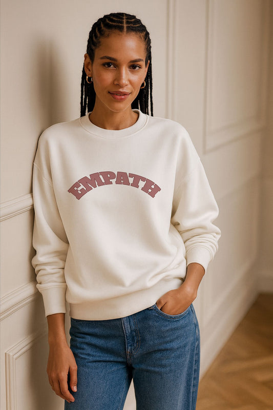 Model wearing FineAF Ivory EMPATH Sweatshirt made from organic cotton fleece, styled with denim jeans in natural daylight studio