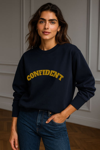 Model wearing FineAF CONFIDENT sweatshirt in navy — unisex organic cotton crewneck, minimalist design with gold arched lettering.