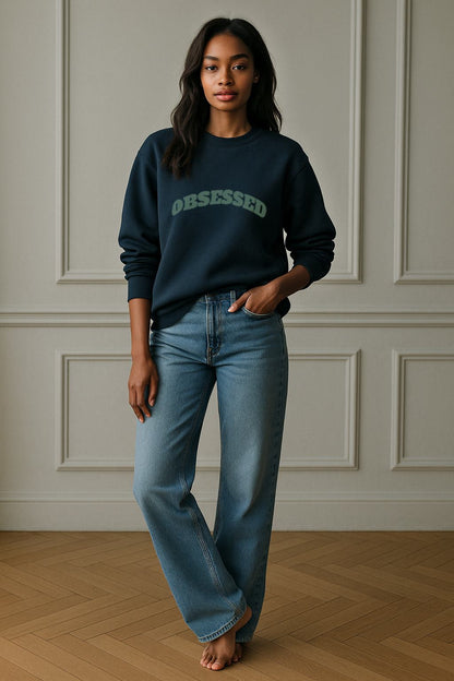 Full-length view of FineAF OBSESSED sweatshirt in blue-teal, styled with light denim jeans.