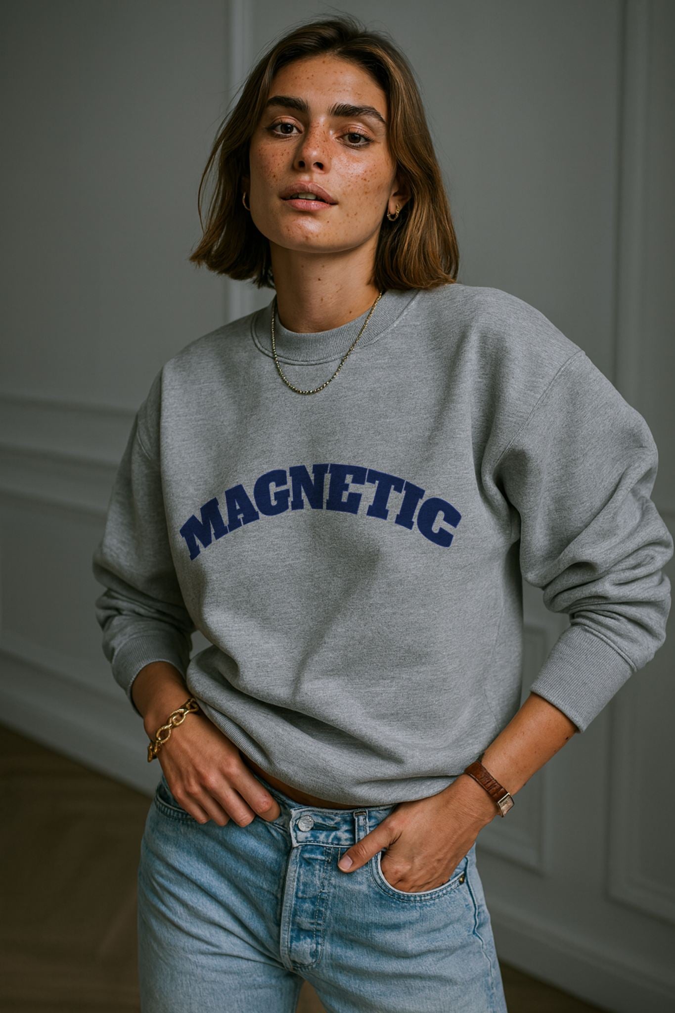 Model wearing FineAF Magnetic Grey Sweatshirt in organic cotton, styled with light denim jeans in studio daylight
