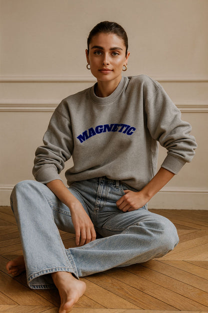 Model in FineAF Magnetic grey unisex sweatshirt, organic cotton fleece with navy lettering, relaxed studio setting