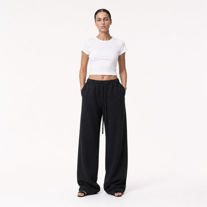 Woman wearing the white FineAF Cropped Tee with black wide-leg pants, front view