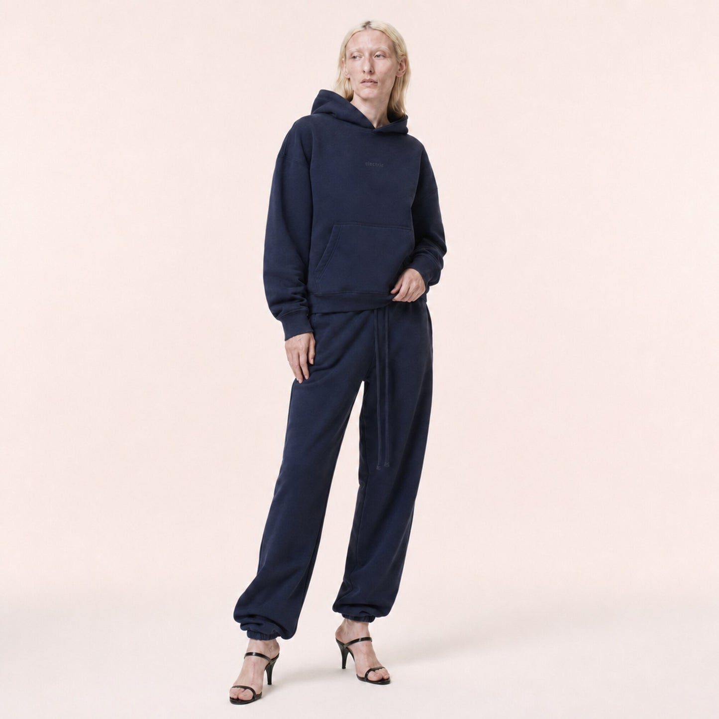 Woman wearing the FineAF Electric deep navy heavyweight hoodie set in an editorial three-quarter pose