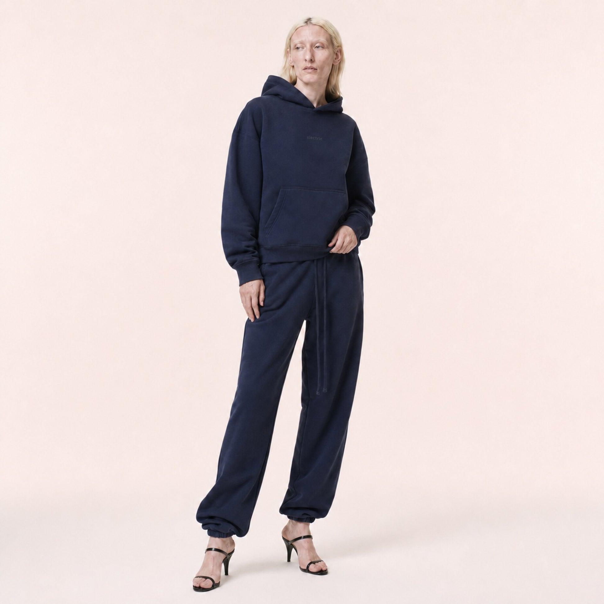 Woman wearing the FineAF Electric deep navy heavyweight hoodie set in an editorial three-quarter pose