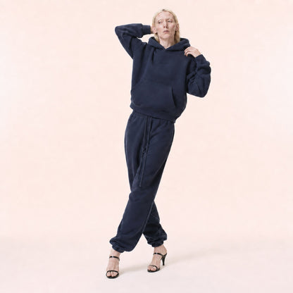 Woman wearing the FineAF Electric deep navy hoodie with raised arms showing its structured fit and hood
