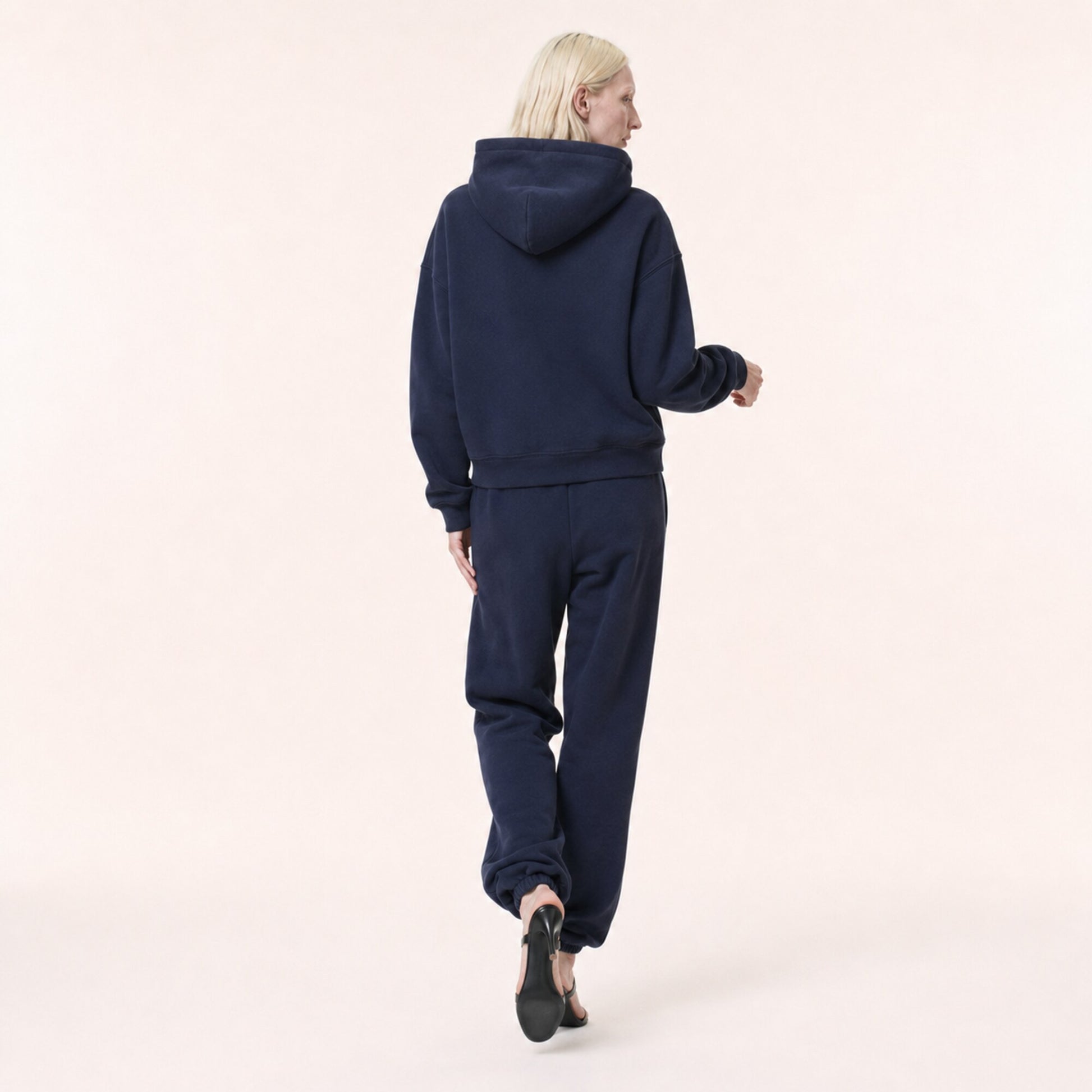 Back view of woman wearing the FineAF Electric deep navy heavyweight hoodie and matching joggers