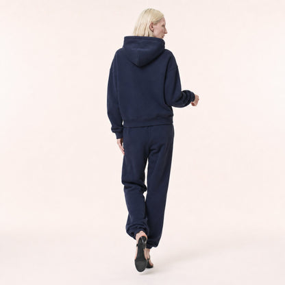 Back view of woman wearing the FineAF Electric deep navy heavyweight hoodie and matching joggers