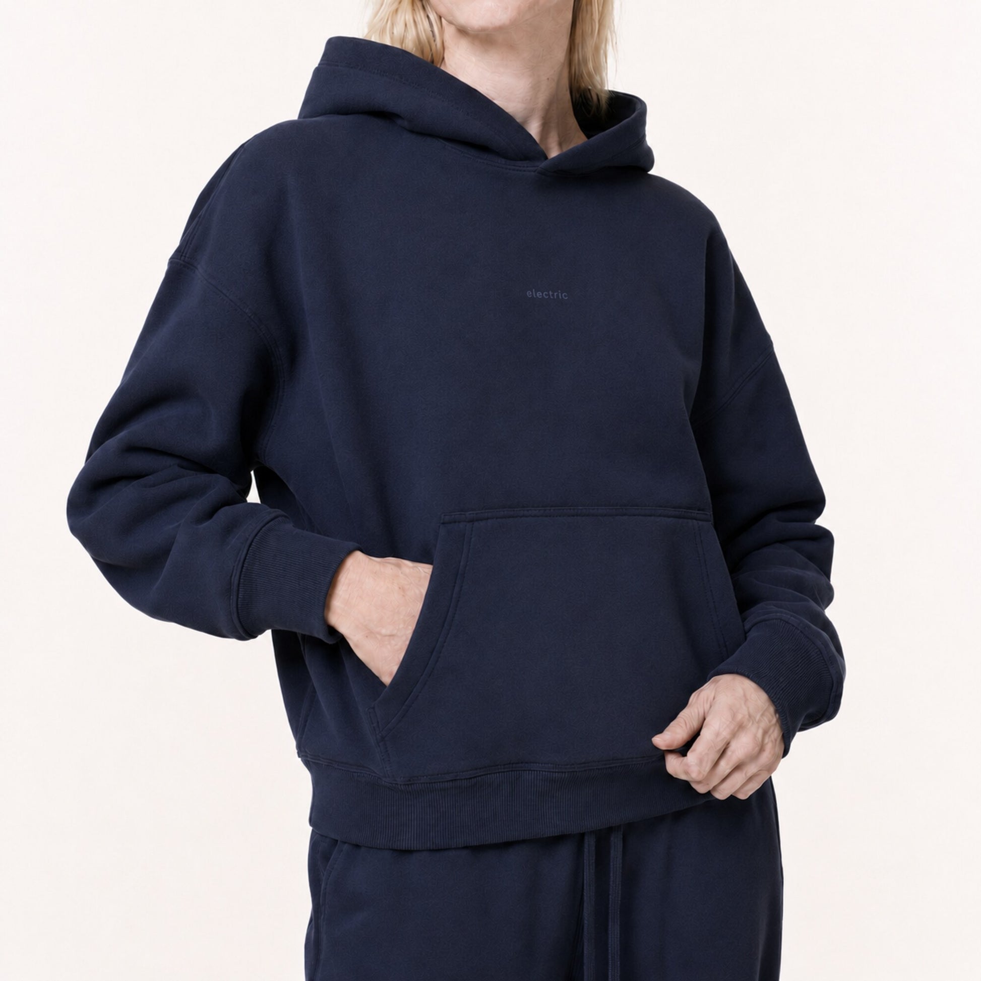 Close model view of the FineAF Electric deep navy hoodie showing the tonal chest design and shaped pocket