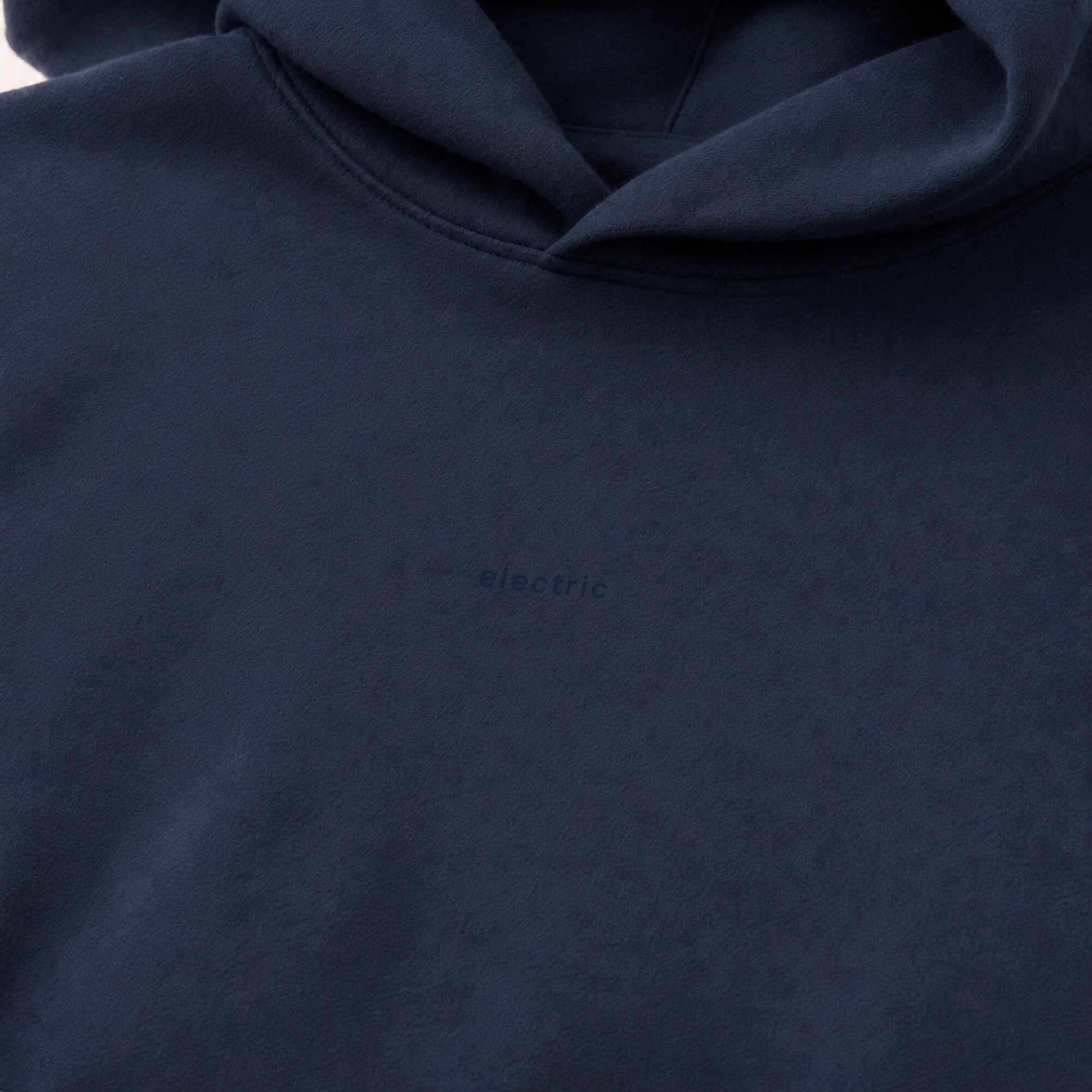 Close-up of the dark tonal electric chest design on deep navy heavyweight fleece