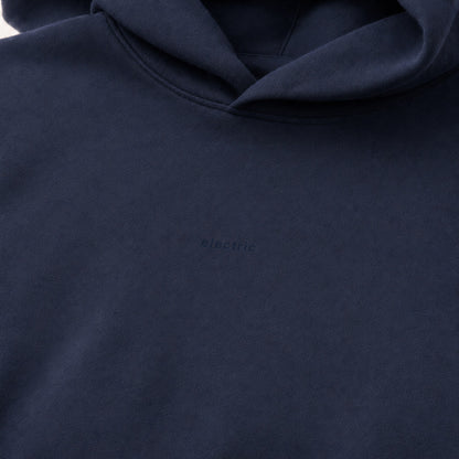 Close-up of the dark tonal electric chest design on deep navy heavyweight fleece