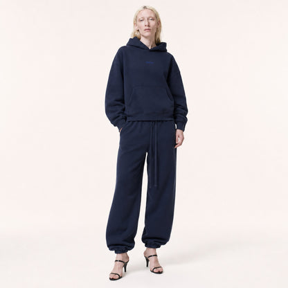 Woman wearing FineAF Electric deep navy oversized tapered pants with a matching hoodie and black heeled sandals, front view.