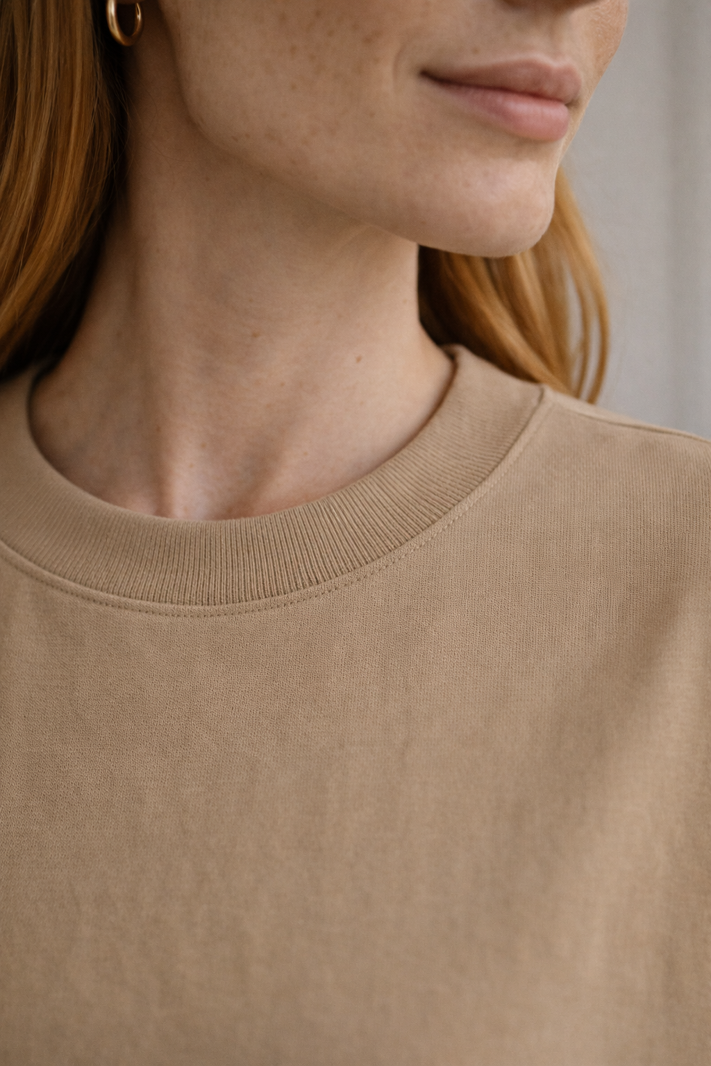 Beige FineAF crewneck T-shirt neckline detail close-up showing ribbed collar and stitching.