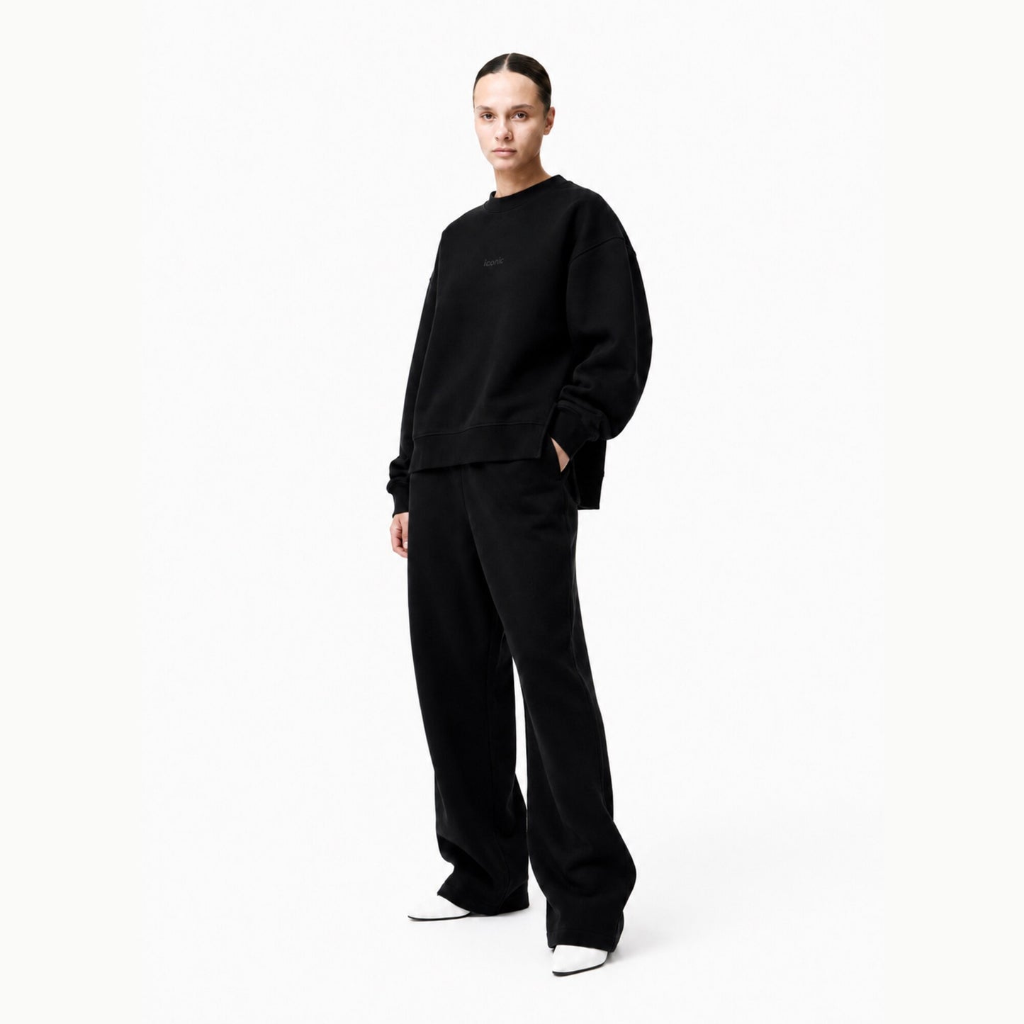 Model wearing the FineAF Iconic black oversized side-slit crewneck sweatshirt with matching black trousers in a bright white studio.