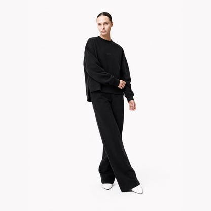 Three-quarter editorial view of the FineAF Iconic black heavyweight crewneck sweatshirt and matching black set.