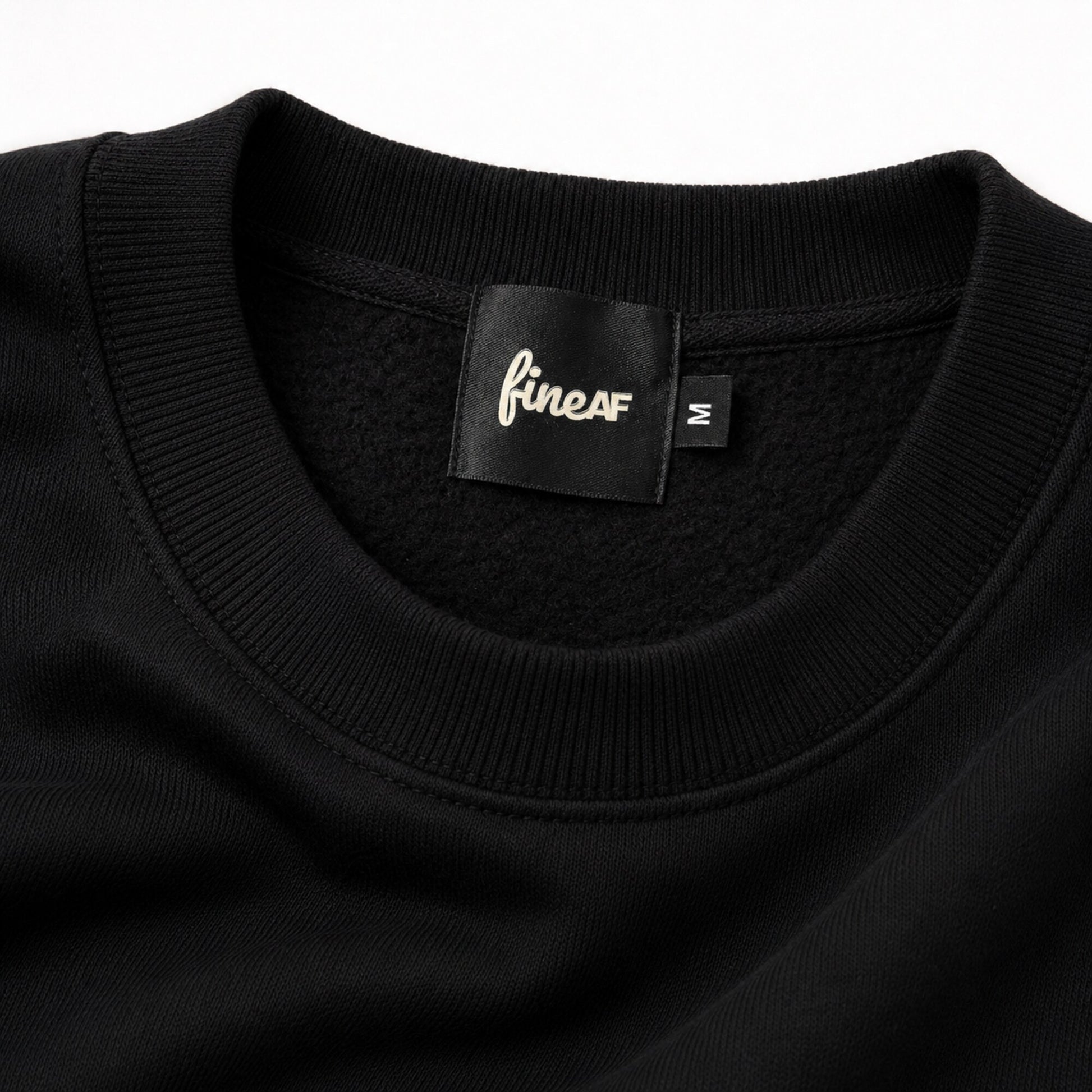 Close-up of the FineAF Iconic black sweatshirt ribbed neckline, brushed fleece interior and black FineAF size M label.