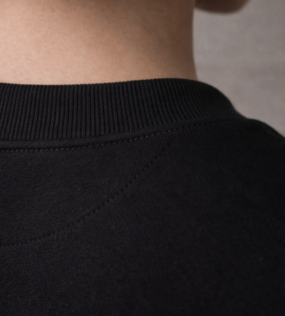 Black FineAF crewneck T-shirt back neckline detail close-up showing ribbed collar and seam.