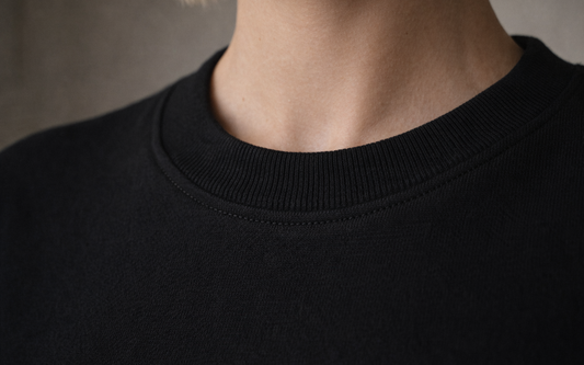 Black FineAF crewneck T-shirt neckline detail close-up showing ribbed collar and stitching.