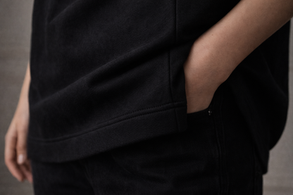 Black FineAF crewneck T-shirt hem and side seam detail, lifestyle close-up on model.
