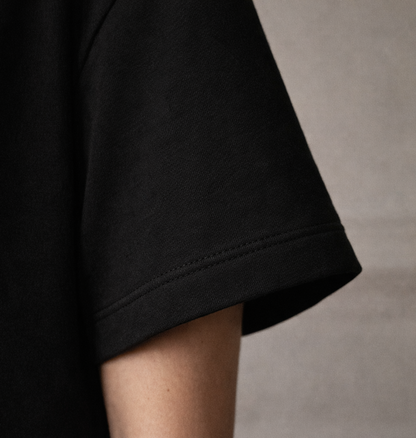 Black FineAF crewneck T-shirt sleeve hem detail close-up showing stitching and fabric texture.