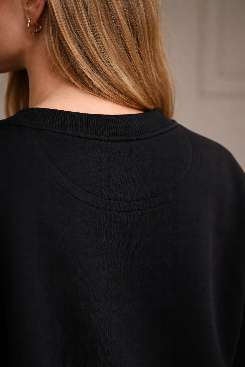 Black FineAF crewneck sweatshirt back neckline close-up showing collar seam and stitching.
