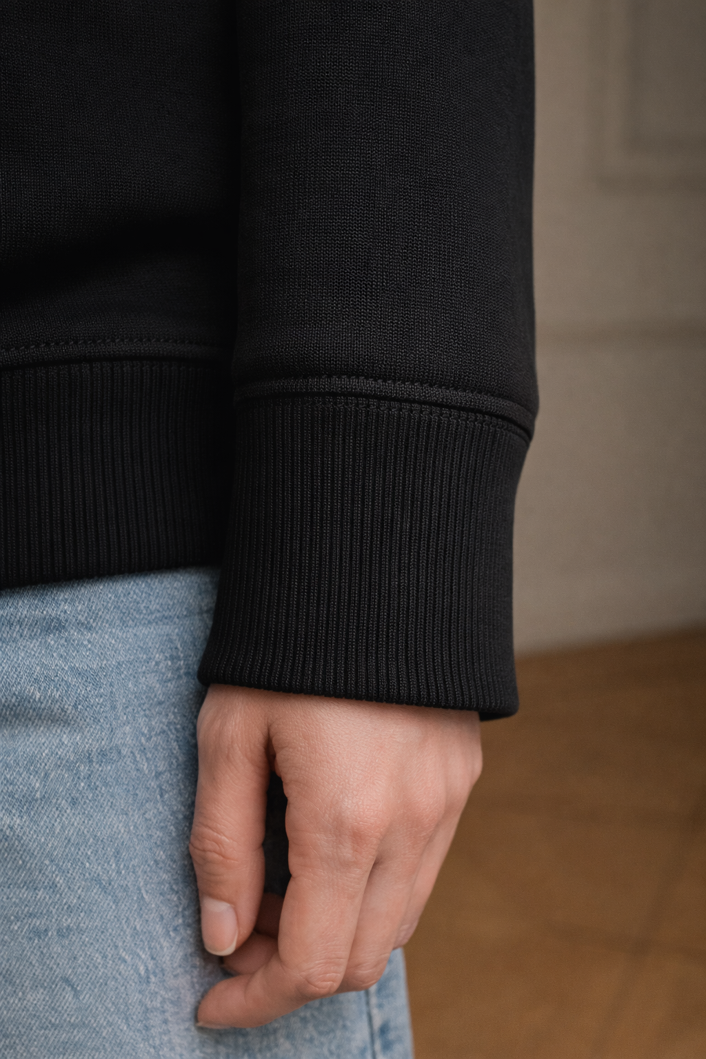 Black FineAF crewneck sweatshirt cuff detail close-up showing ribbed knit sleeve hem.
