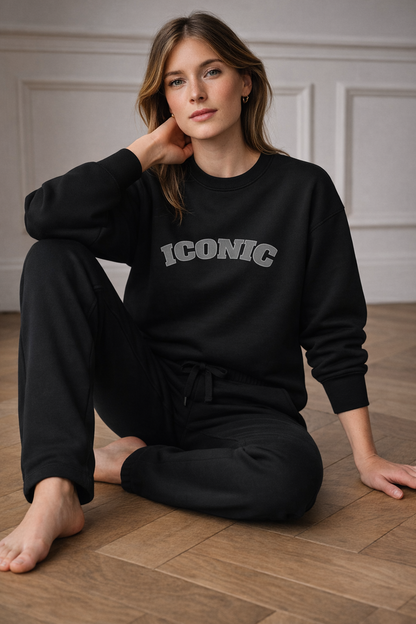 Black FineAF crewneck sweatshirt with “ICONIC” print, seated lifestyle photo on model.