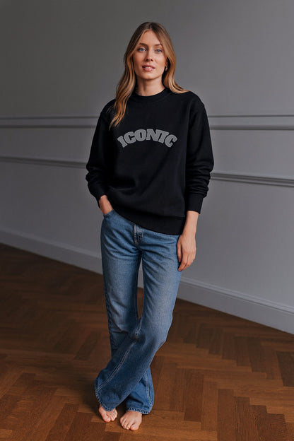 Black ICONIC heavyweight organic cotton crewneck sweatshirt with relaxed unisex fit, worn in a daylight studio.