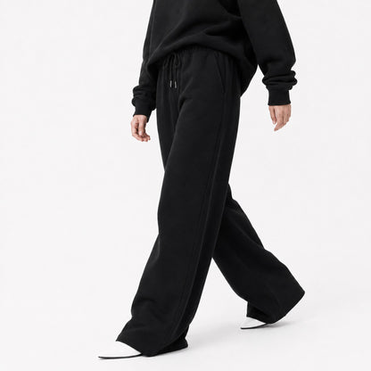 FineAF Iconic black wide straight-leg pants shown in an editorial walking pose with open hems