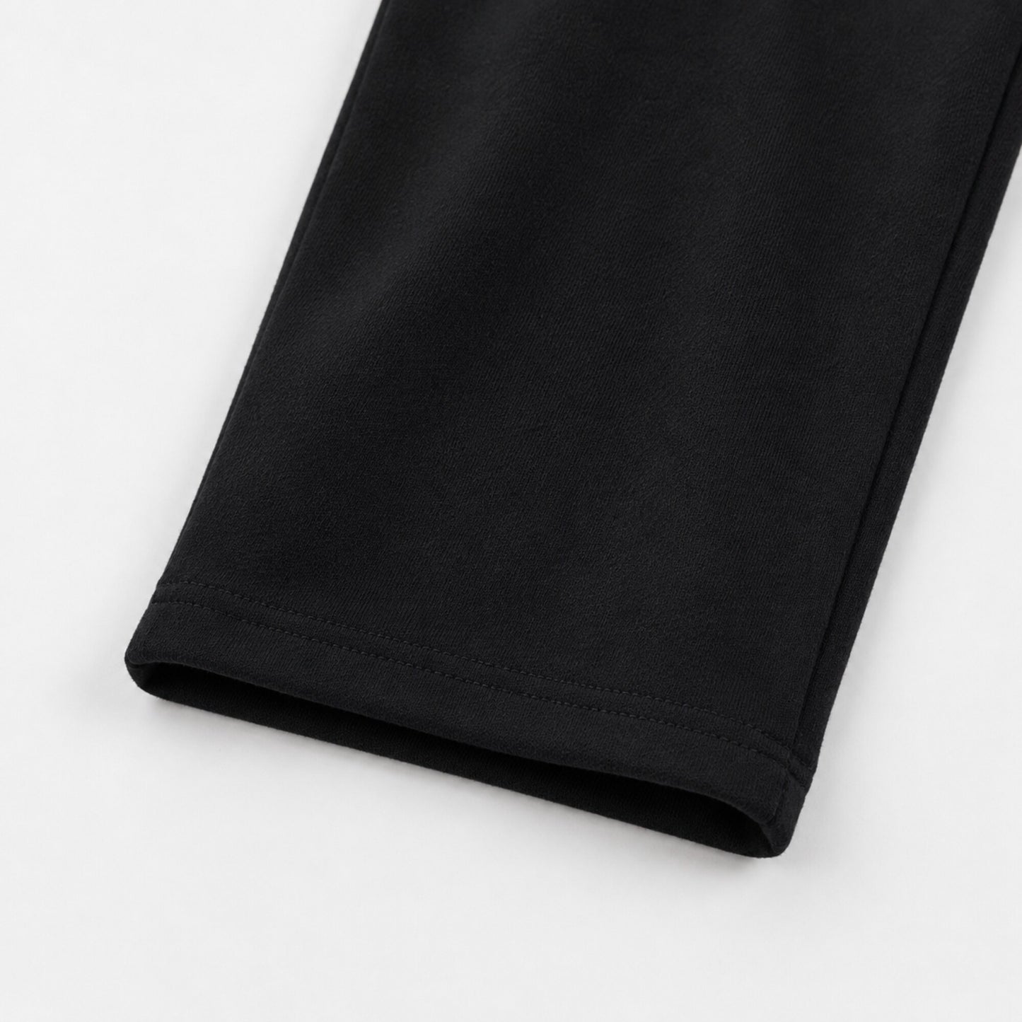 Close-up of the open hem and tonal stitching on FineAF Iconic black straight-leg pants