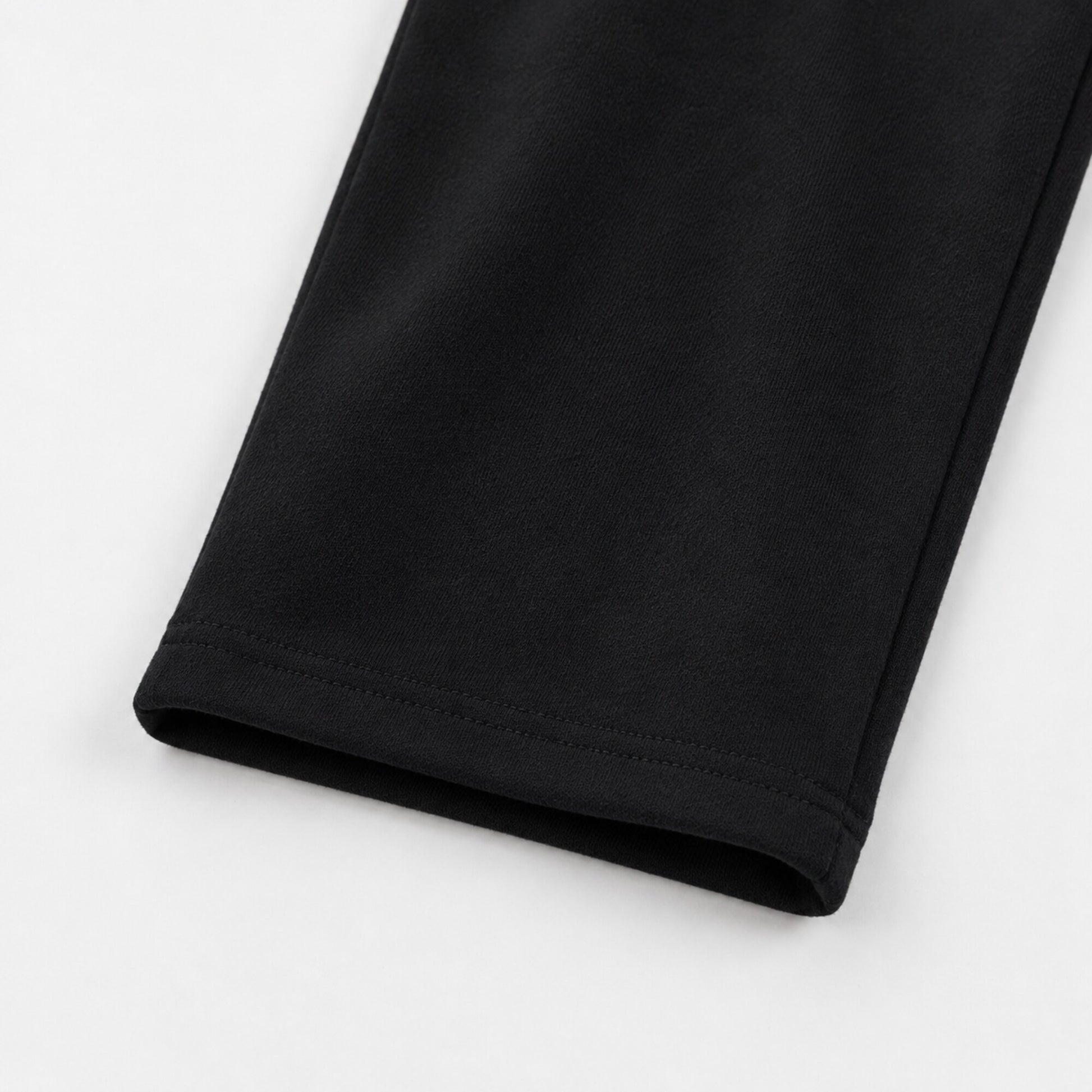 Close-up of the open hem and tonal stitching on FineAF Iconic black straight-leg pants