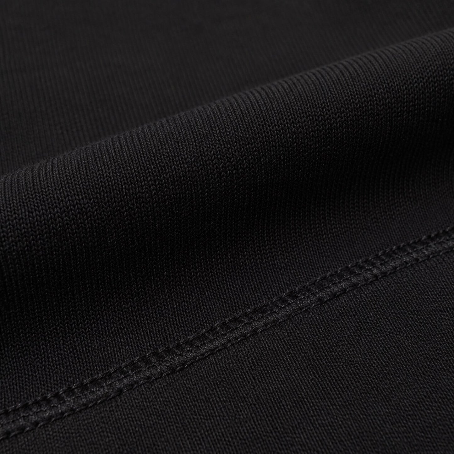 Macro view of the dense matte black fabric and tonal seam on FineAF Iconic pants