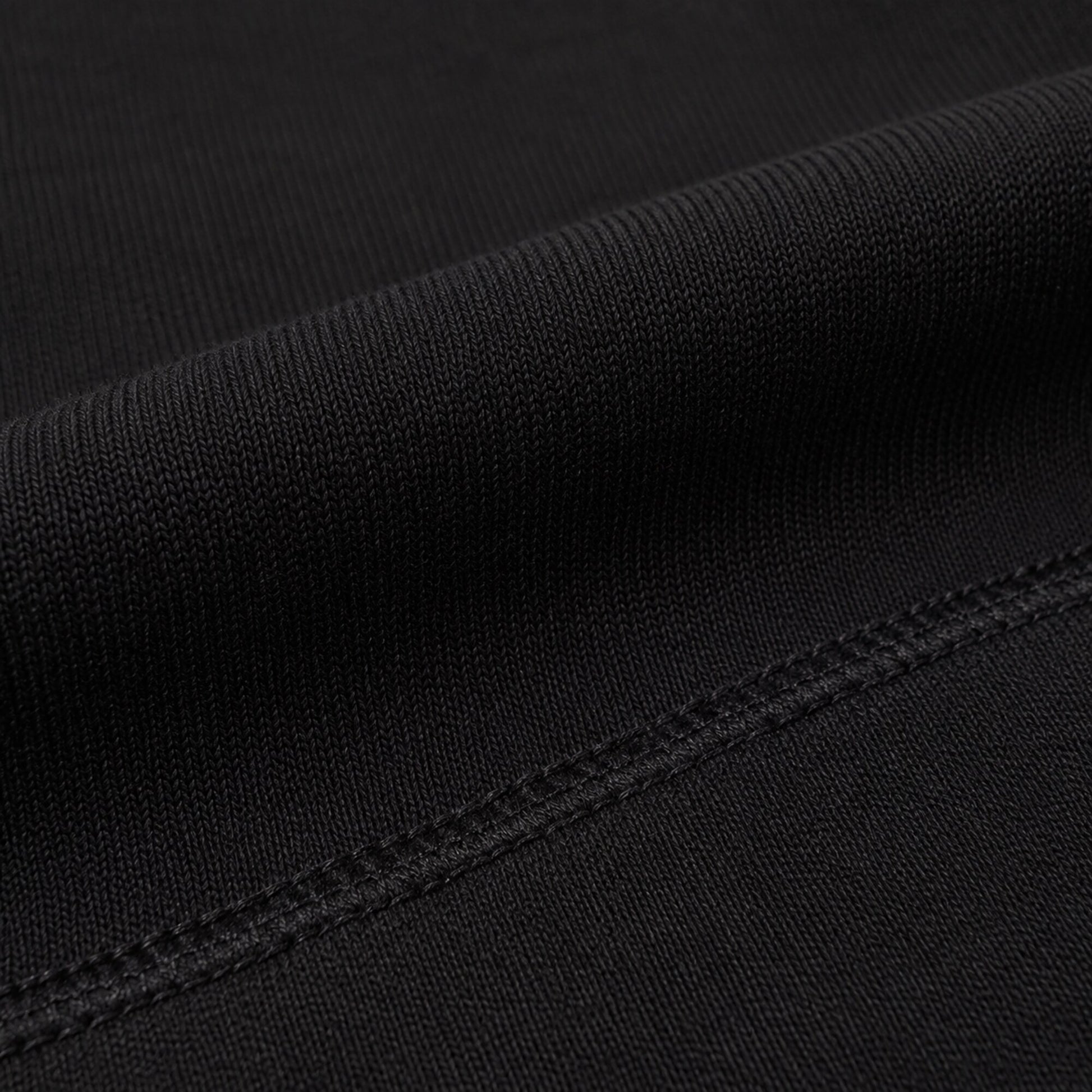 Macro view of the dense matte black fabric and tonal seam on FineAF Iconic pants