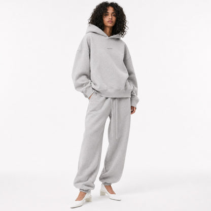 Model wearing the FineAF Magnetic heather grey oversized hoodie with matching joggers and white heels, front view