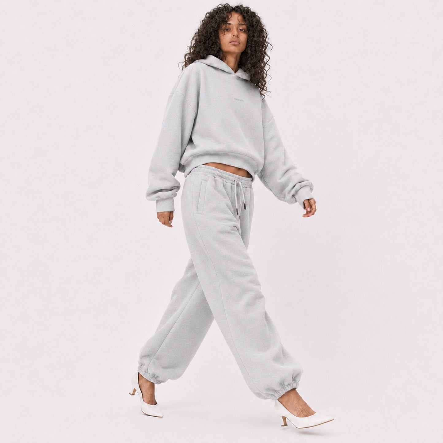 Woman walking in oversized light grey FineAF Magnetic pants and matching cloudy hoodie