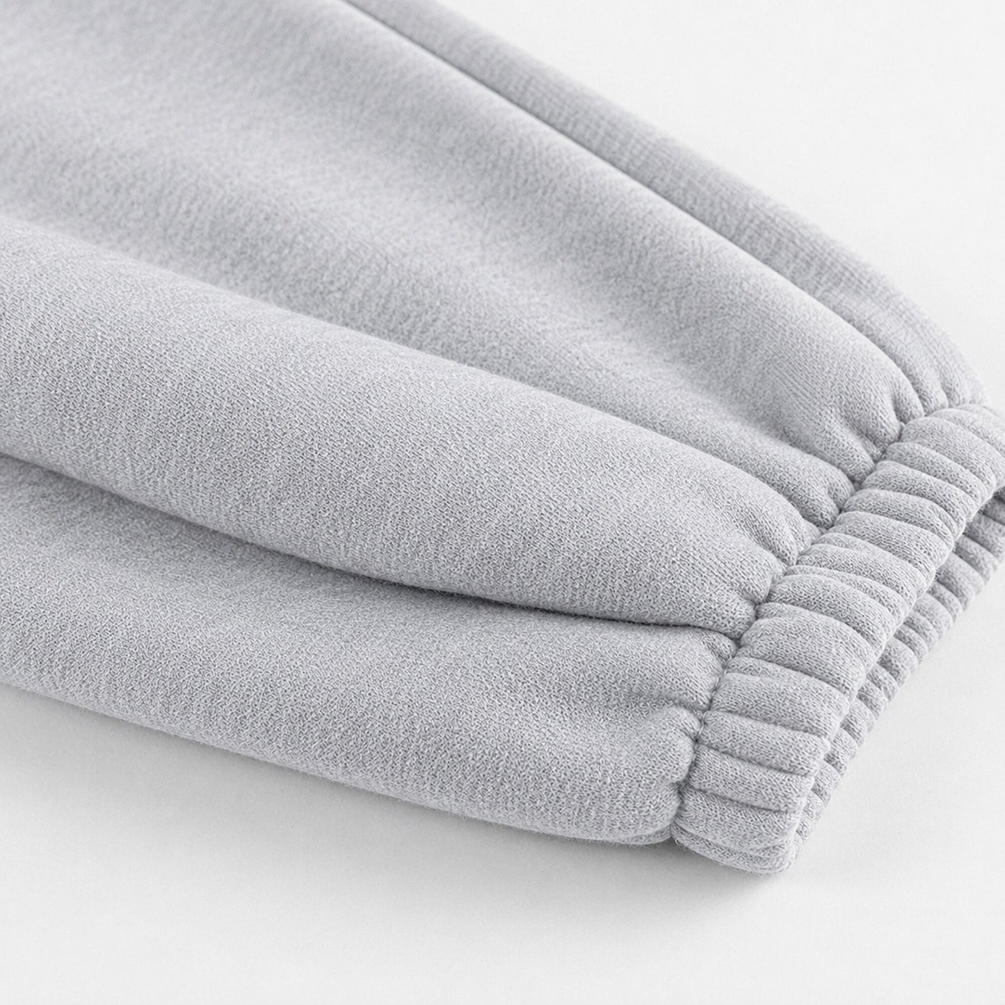 Close-up of the gathered elastic ankle construction on light grey FineAF Magnetic pants