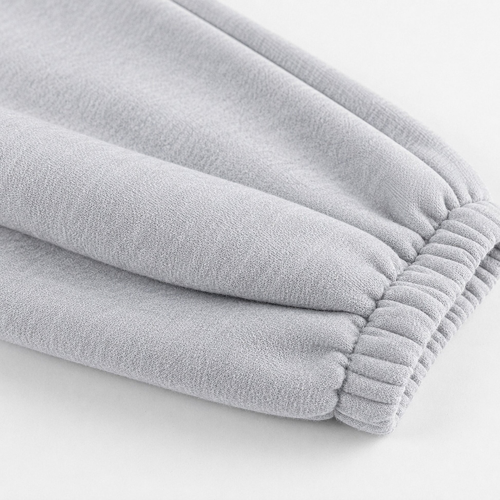 Close-up of the gathered elastic ankle construction on light grey FineAF Magnetic pants