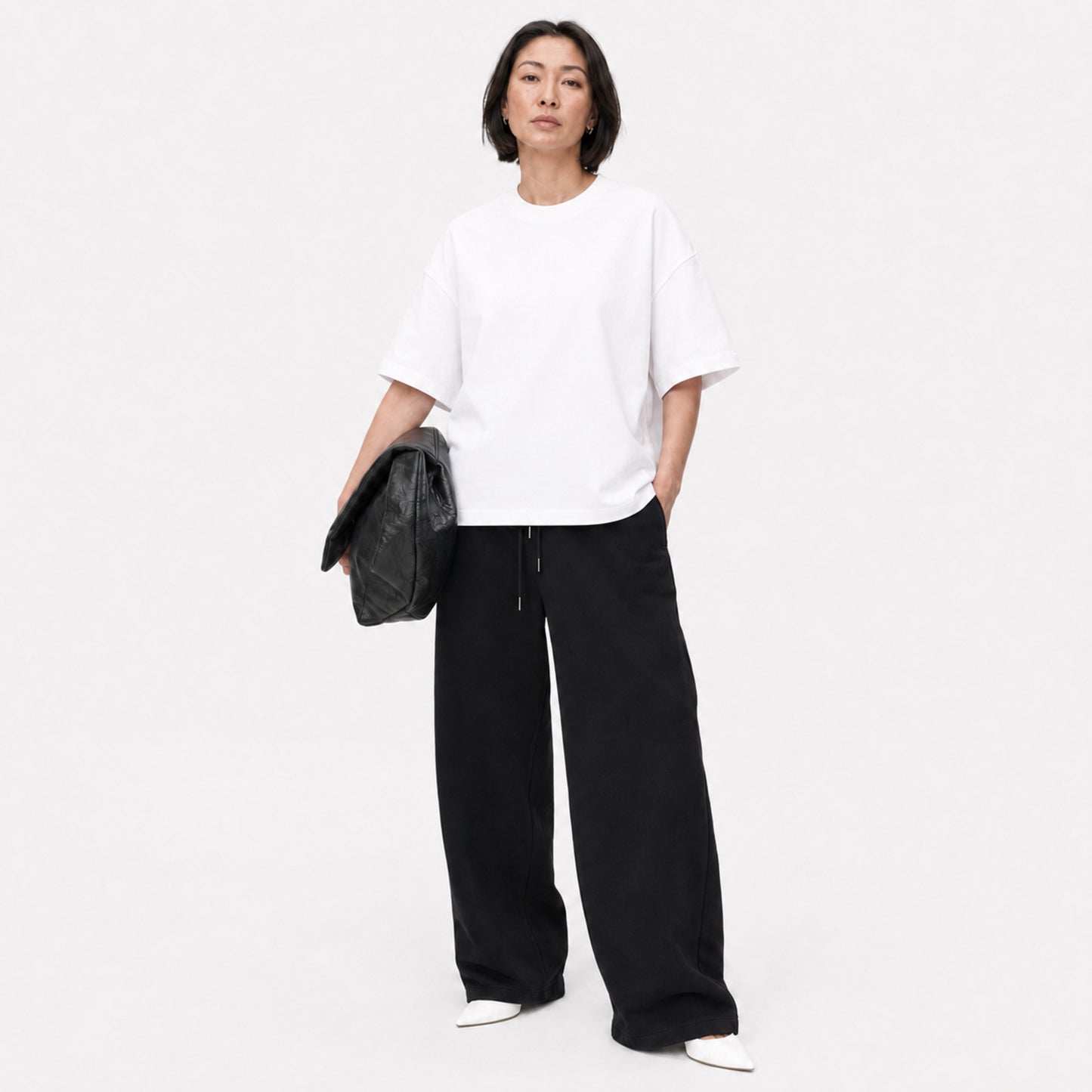 Woman wearing the white FineAF Boxy Tee with black wide-leg pants in a bright studio