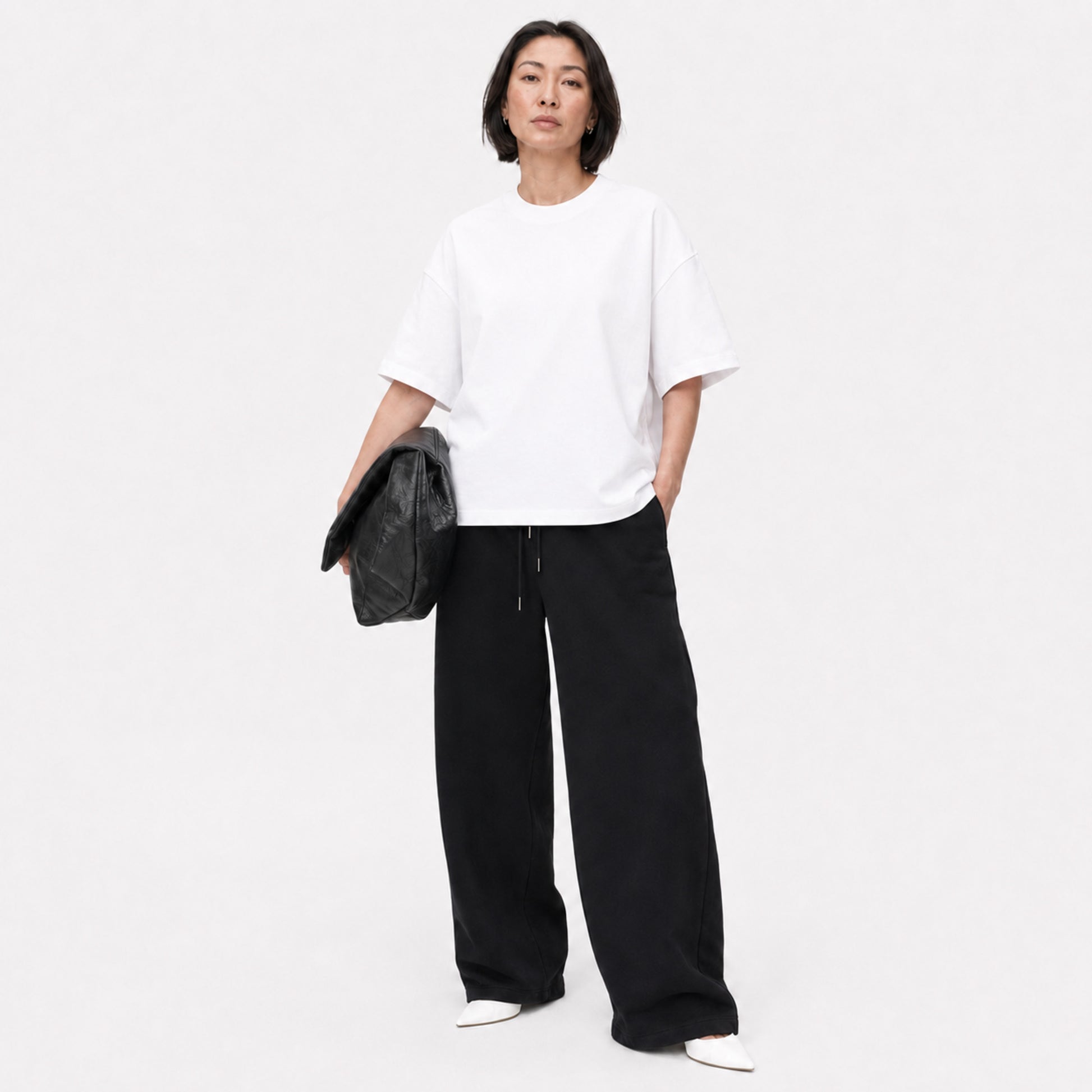 Woman wearing the white FineAF Boxy Tee with black wide-leg pants in a bright studio