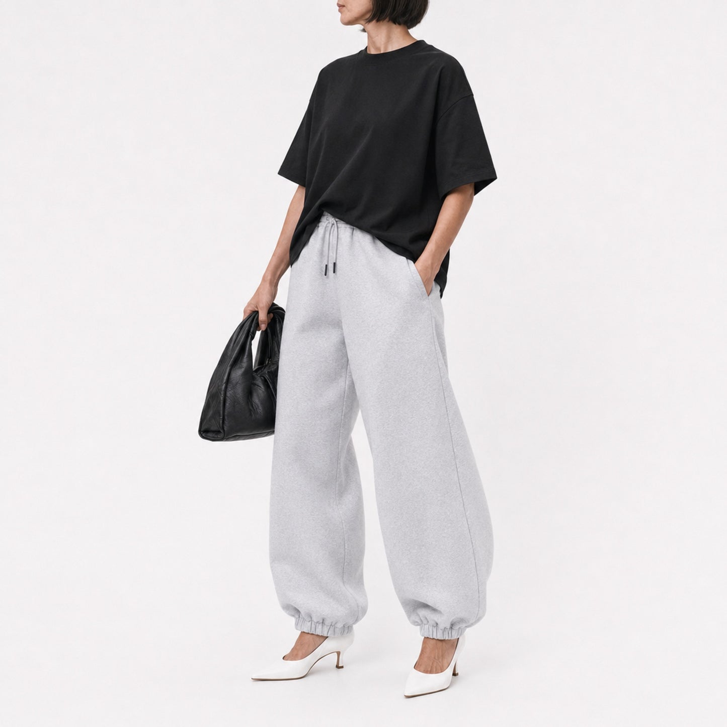 Woman wearing the black FineAF Boxy Tee with grey joggers, editorial three-quarter view