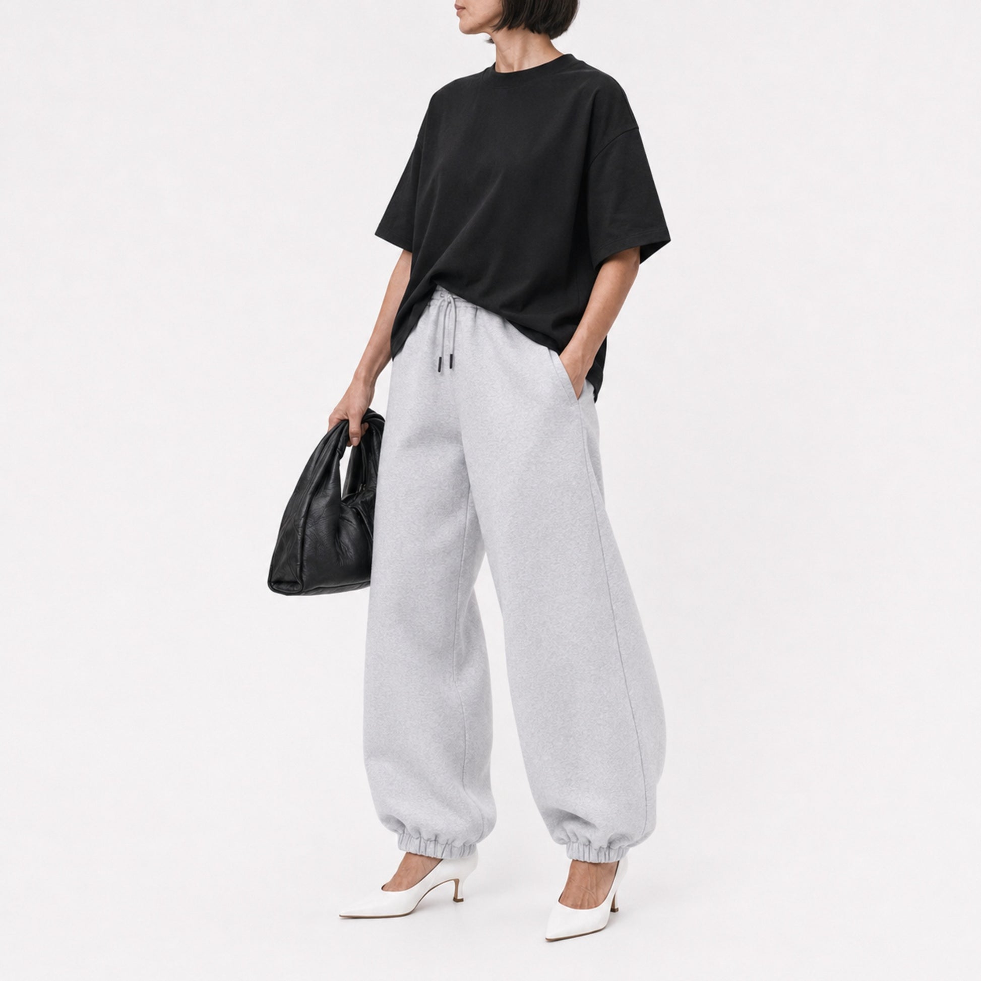 Woman wearing the black FineAF Boxy Tee with grey joggers, editorial three-quarter view