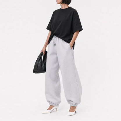 Woman wearing the black FineAF Boxy Tee with grey joggers, editorial three-quarter view