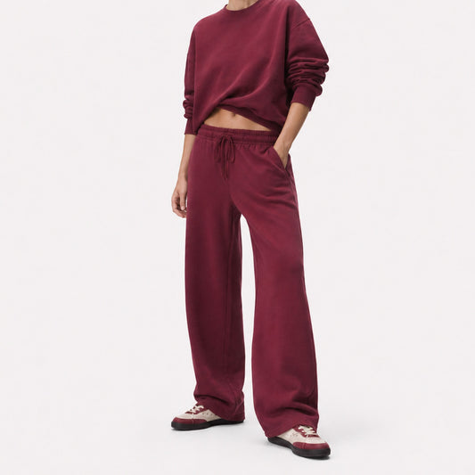 Three-quarter view of oversized FineAF Visionary wine pants styled with the matching crewneck and wine-and-cream sneakers.