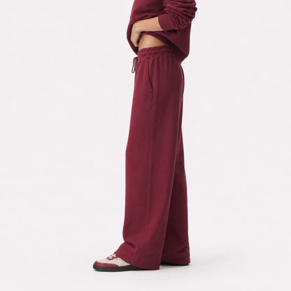 Side profile of FineAF Visionary wine pants showing the gathered waist, relaxed straight leg and open hem.