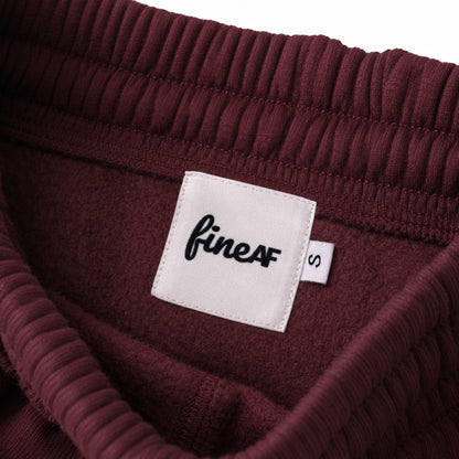 Inside waistband of FineAF Visionary wine pants with white FineAF woven label and S size tab.