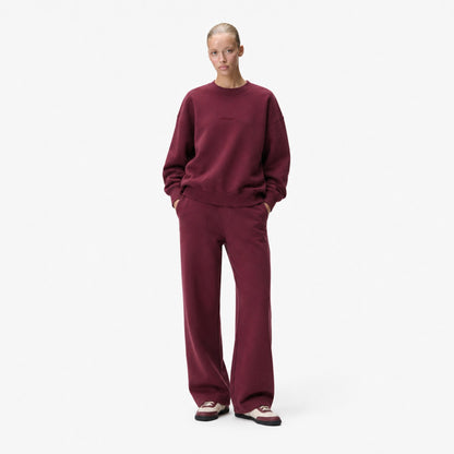 Woman wearing the FineAF Visionary wine sweatshirt with matching straight-leg sweatpants and sneakers, front view